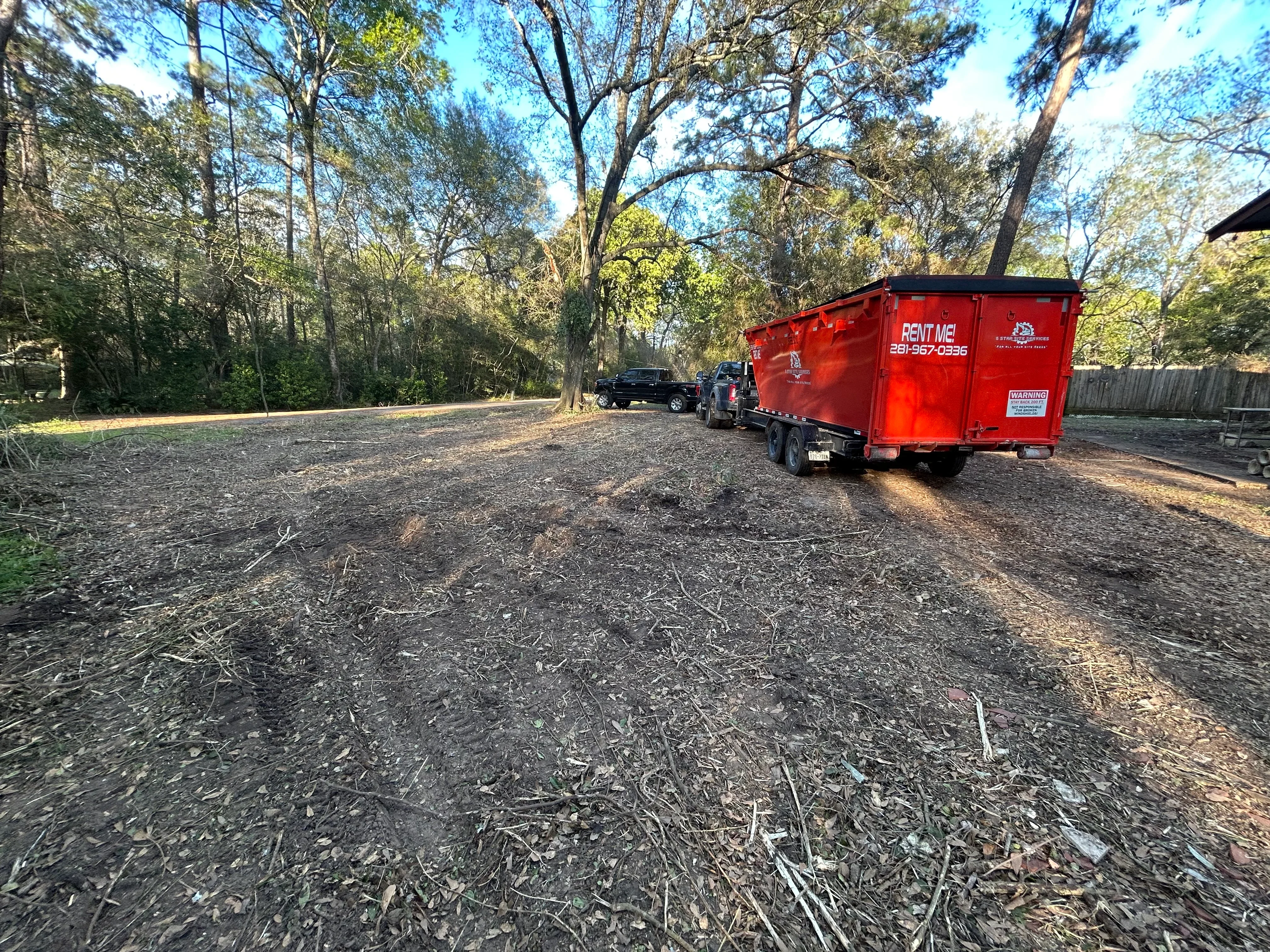 Cleared wooded lot with debris removal truck and equipment on site