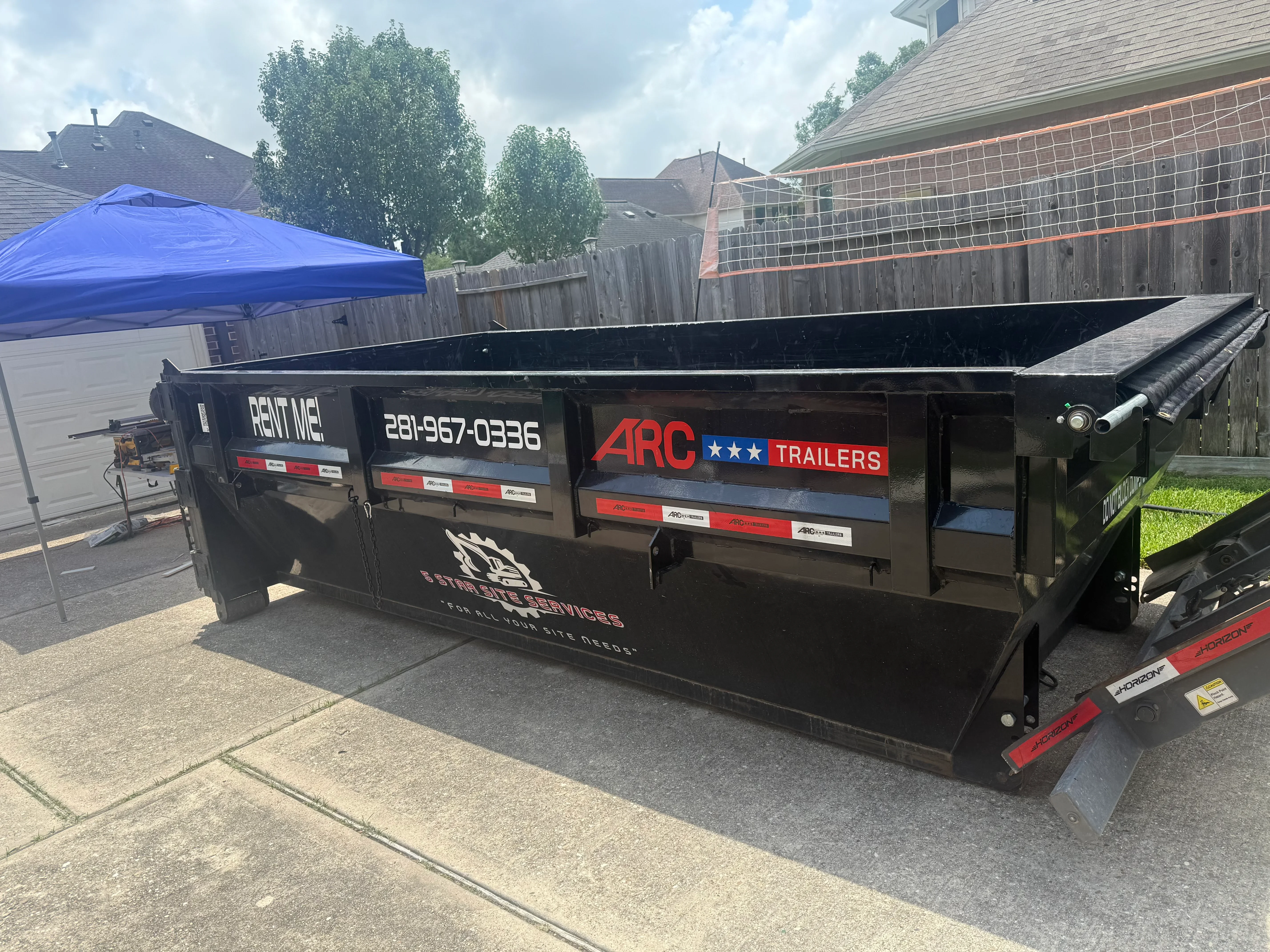 Black dump trailer with custom vinyl wrap, red and white graphics, and company branding
