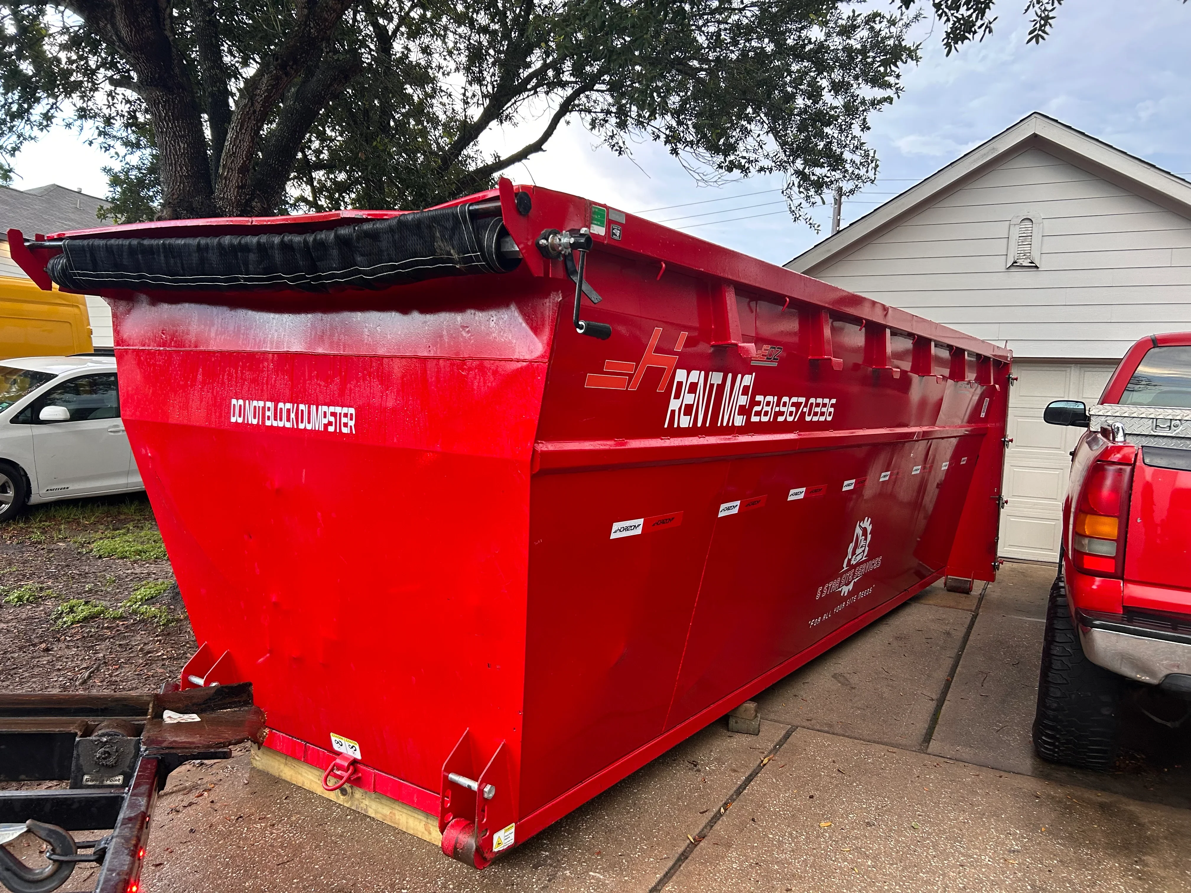 Red roll-off dumpster with hydraulic lift and black tarp cover system