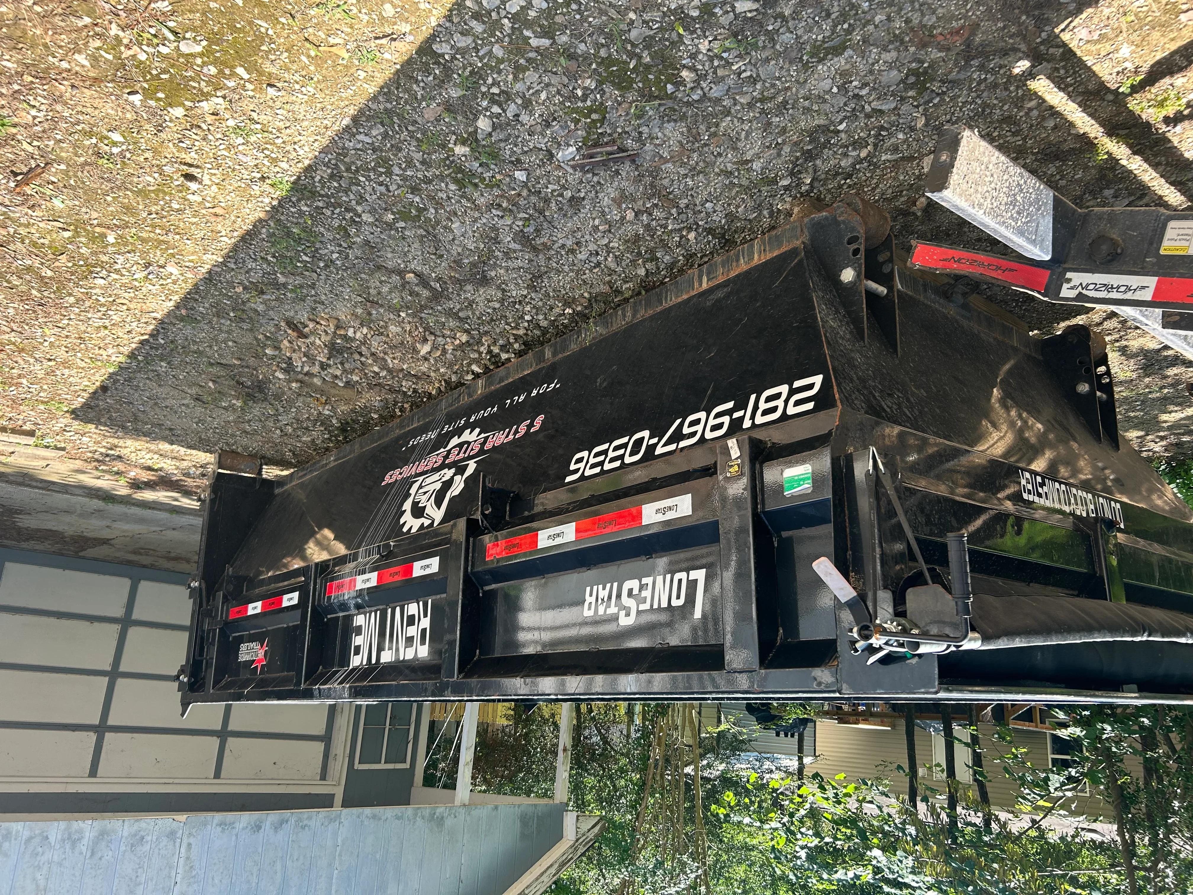 Black steel roll-off dumpster with red and white safety markings loaded with construction debris