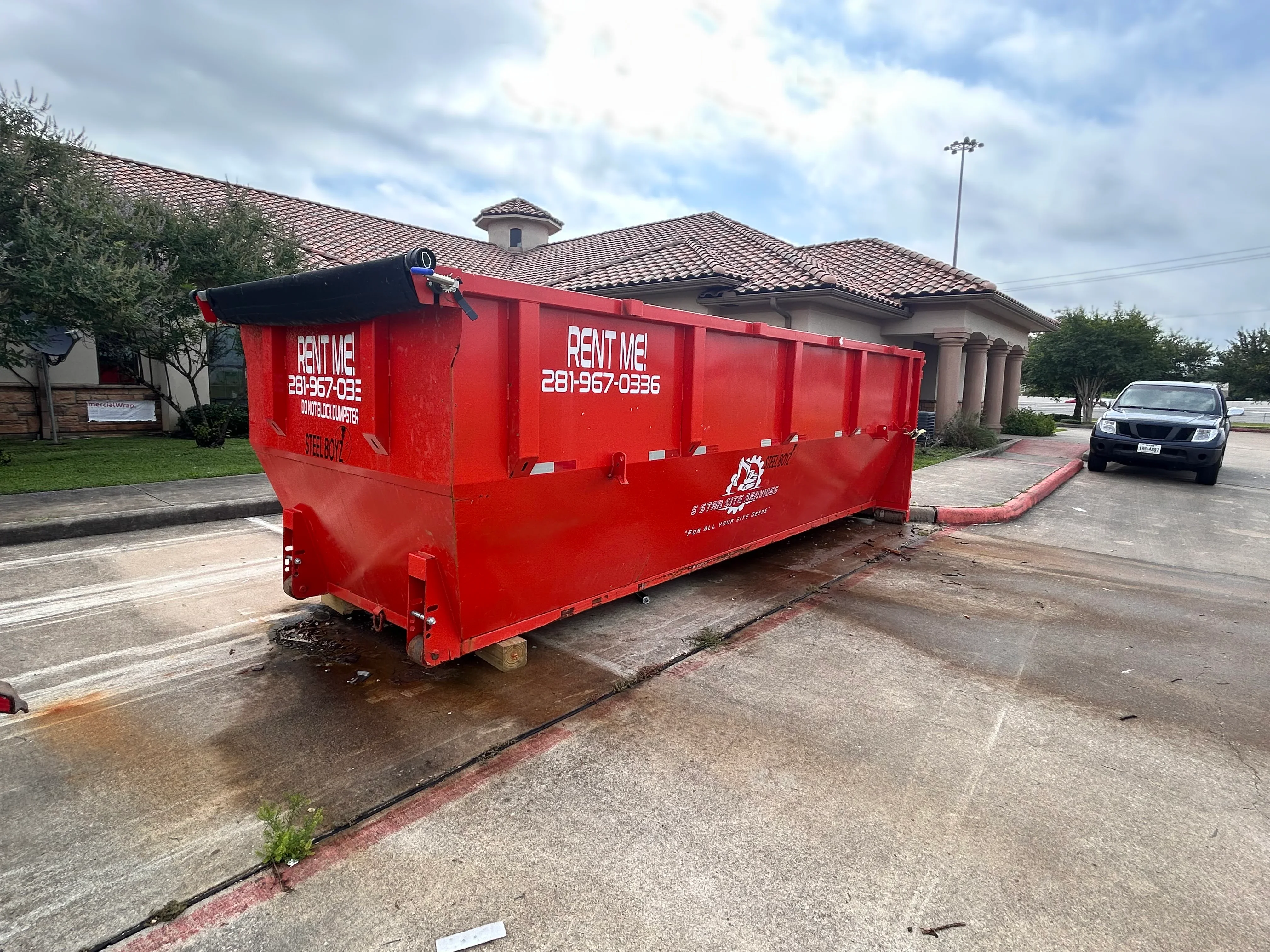 Red dumpster container on concrete pad at commercial property