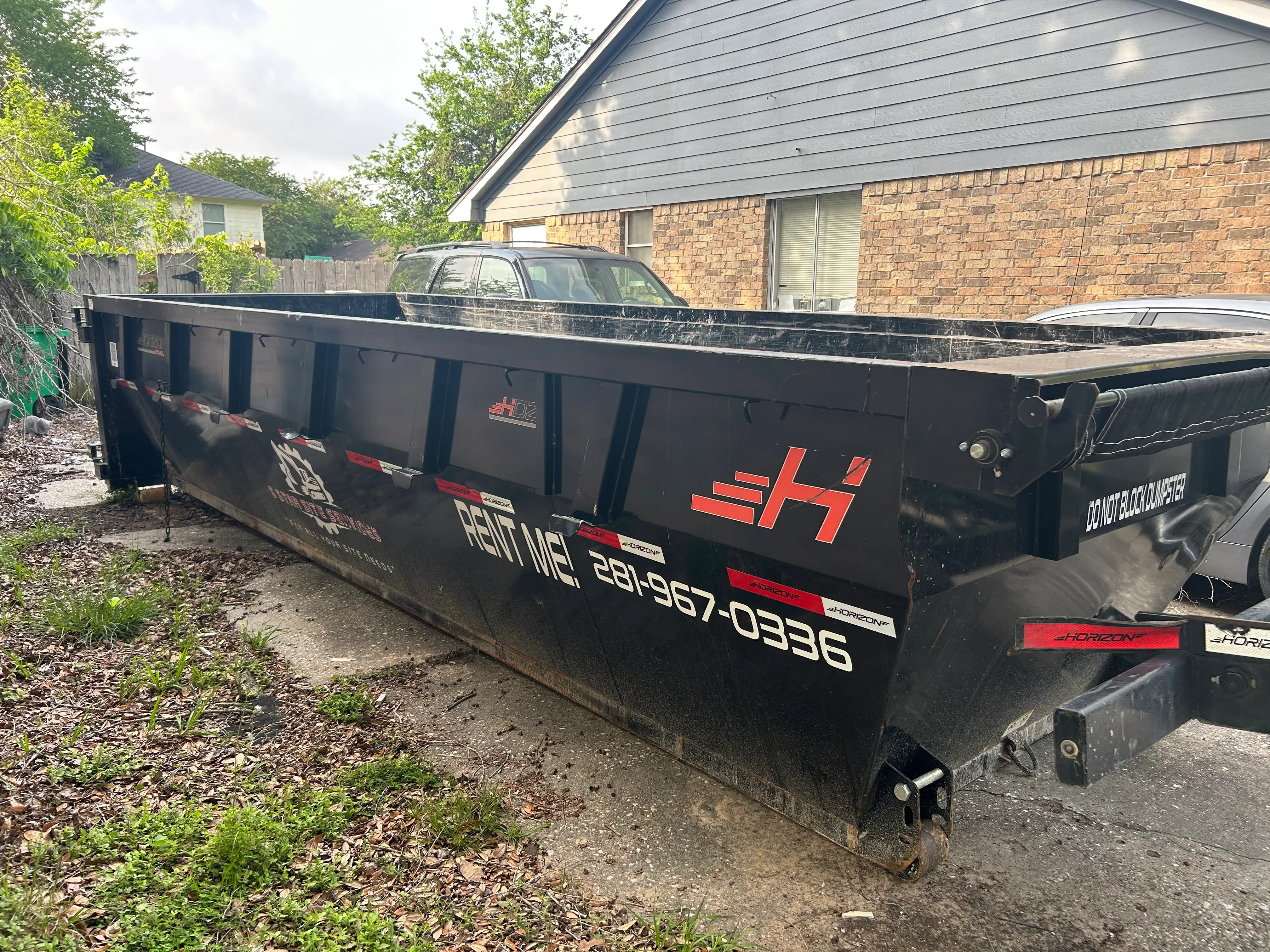 Black steel roll-off dumpster with red branding, open-top design for debris hauling